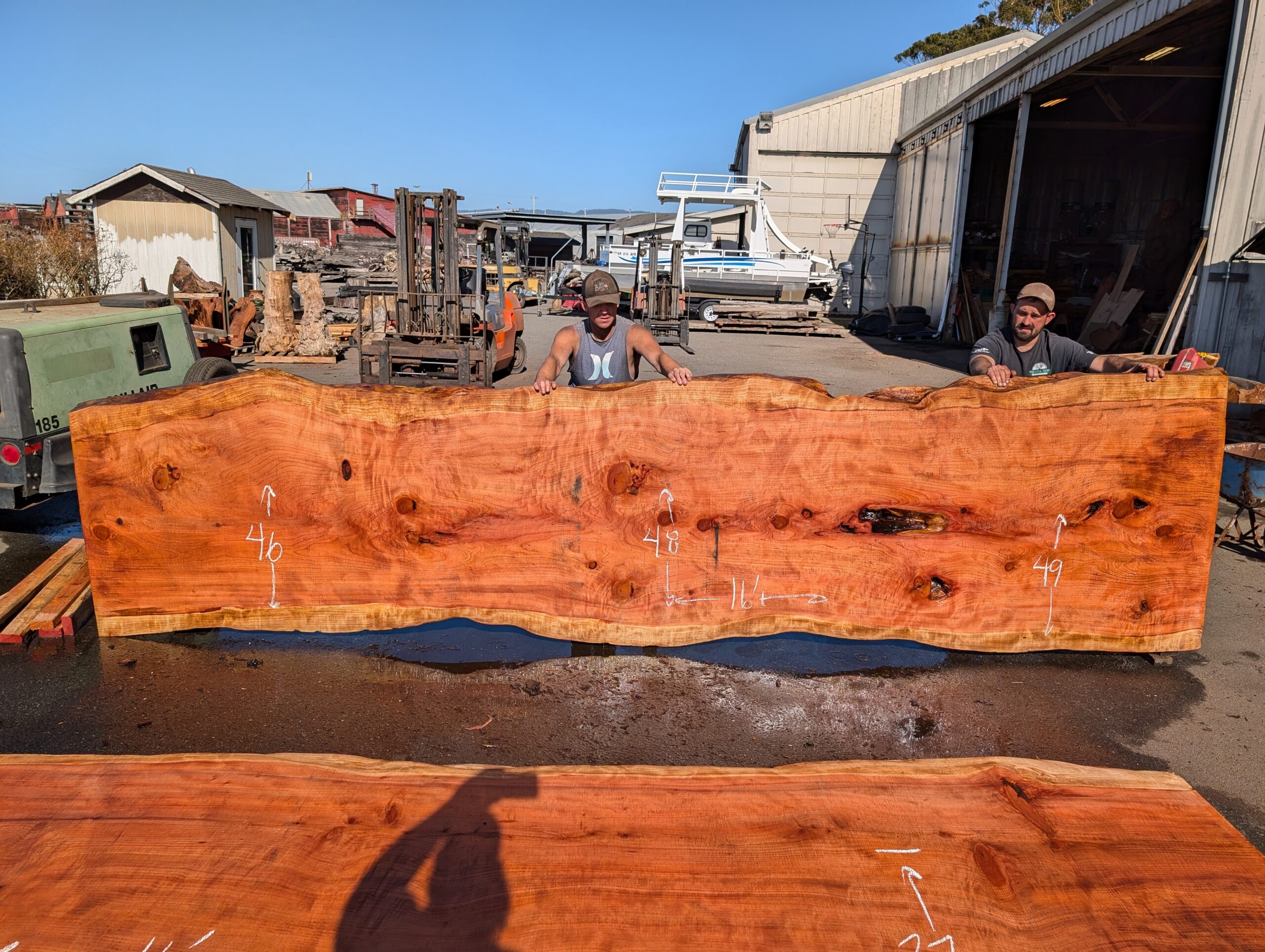 Redwood table top measuring 16 feet long by 47 to 49 inches wide and 3 inches thick.